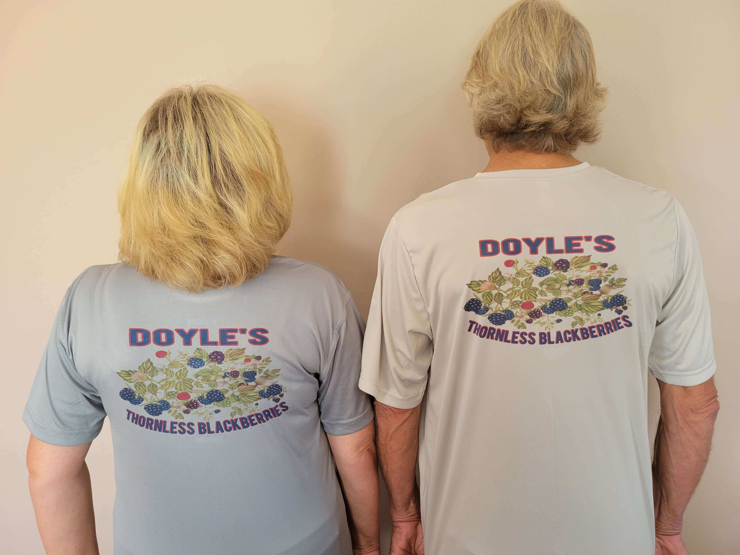 Two people wearing Doyle's Thornless Blackberries T-shirts, showcasing the vibrant back design.