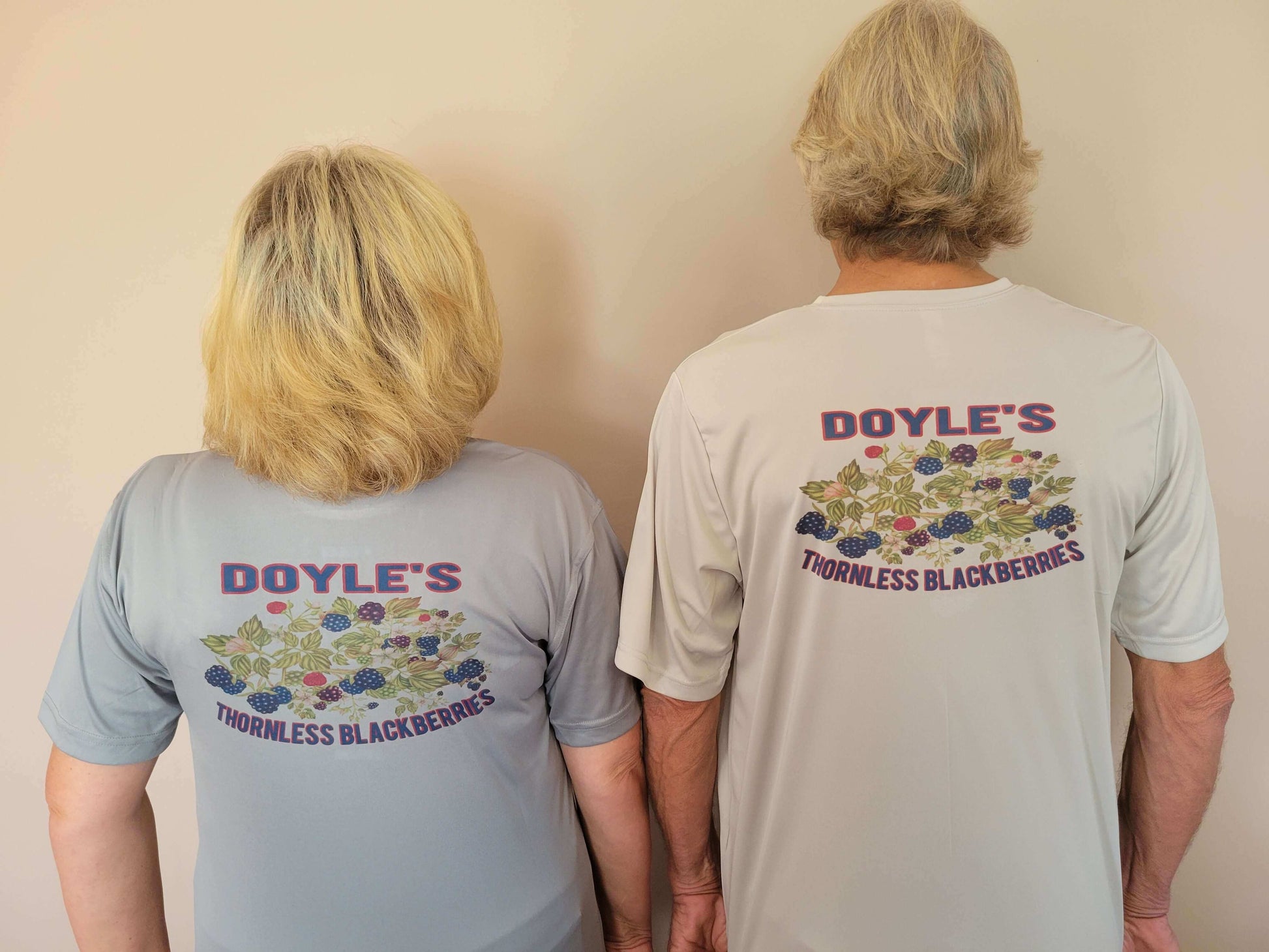 Two people wearing Doyle's Thornless Blackberries T-shirts, showcasing the vibrant back design.