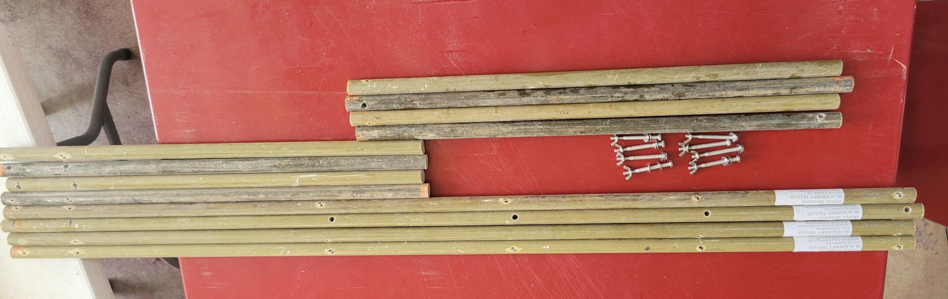 Doyle Trailing Blackberry Shift Trellis components including fiberglass rods and stainless steel hardware on a red table.